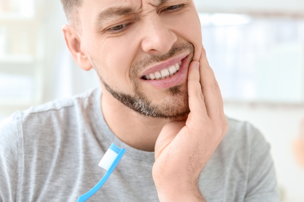 Young man suffering from toothache indoors